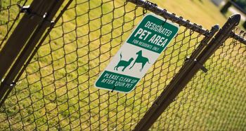 A sign on a fence designates an area for pets.